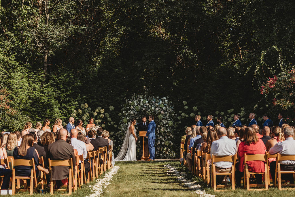 Elegant backyard wedding ceremony in Pennsylvania, with Christine and Michael exchanging vows under a floral arch