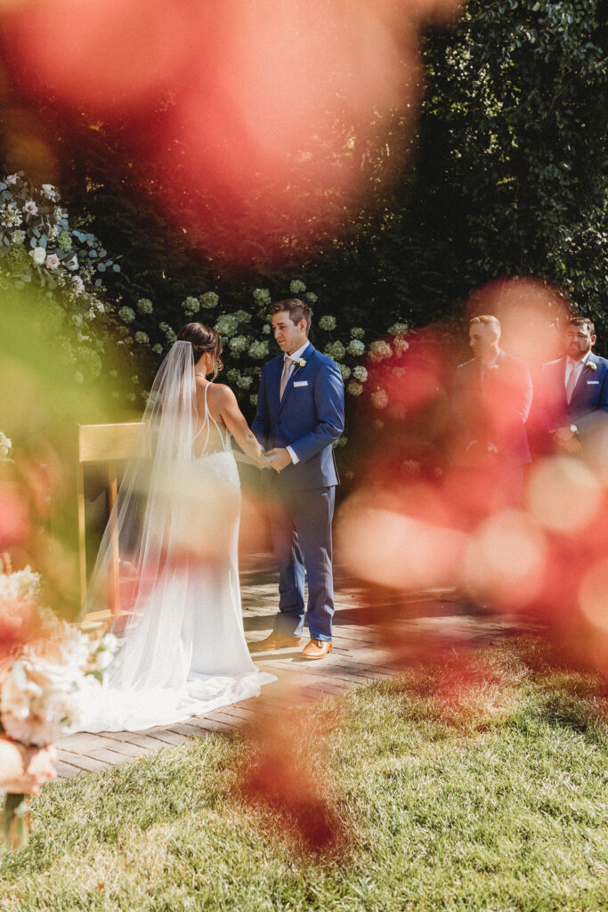 Elegant backyard wedding ceremony in Pennsylvania, with Christine and Michael exchanging vows under a floral arch