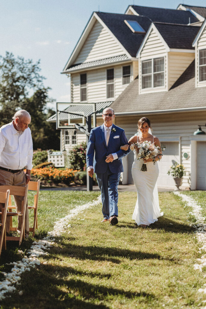 Elegant backyard wedding ceremony in Pennsylvania, with Christine and Michael exchanging vows under a floral arch