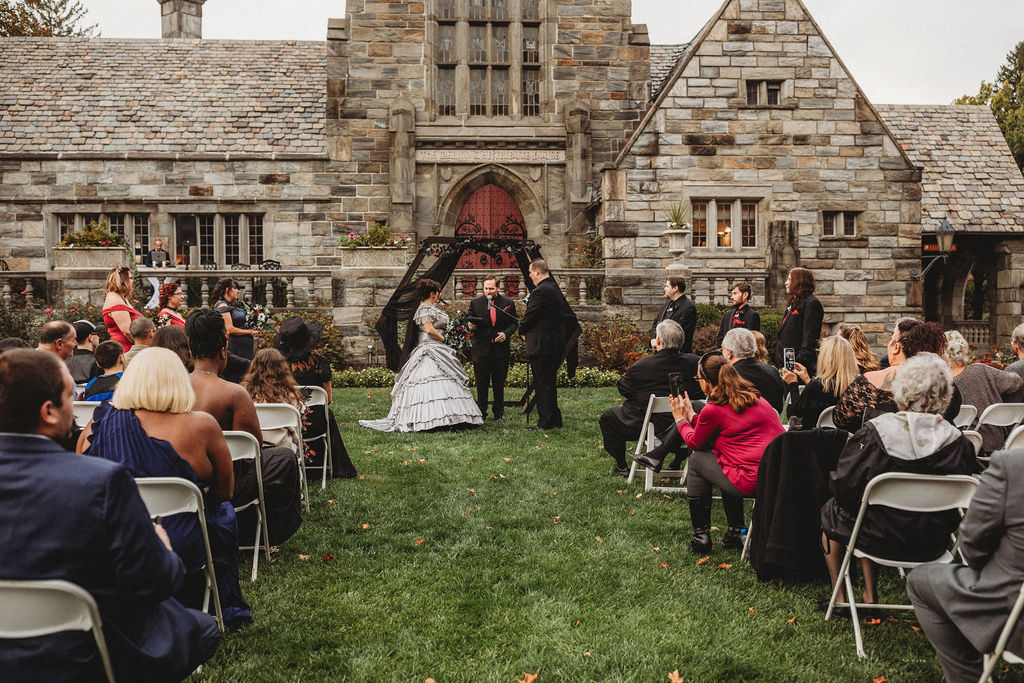 bride and groom exchanging vows with an old, historic mansion in the backdrop