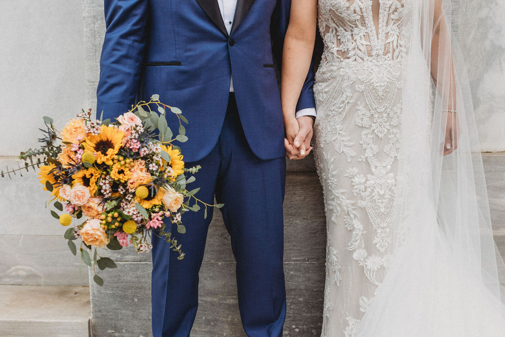 the wedding couple holding hands at the merchants exchange building