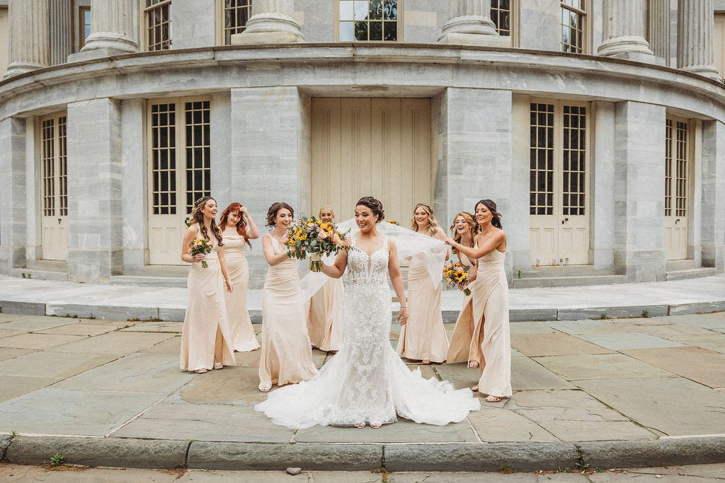 bride and bridesmaids in neutral bridesmaid dresses at the merchants exchange building in philadelphia