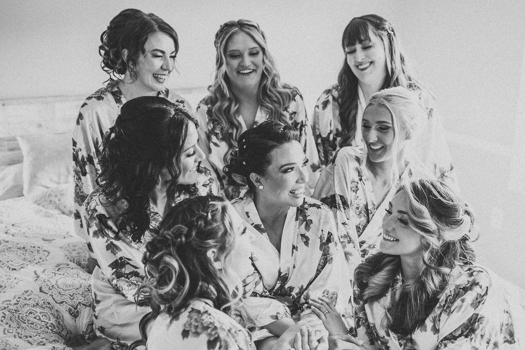 bride and bridesmaids sitting on the bed in matching robes