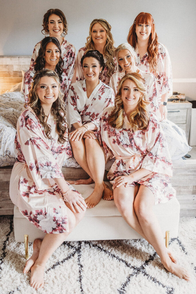 bride and bridesmaids sitting on the bed in matching robes